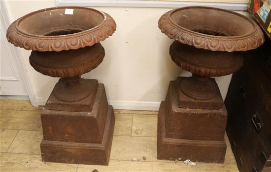 A pair of cast iron urns and pedestals, W.50cm